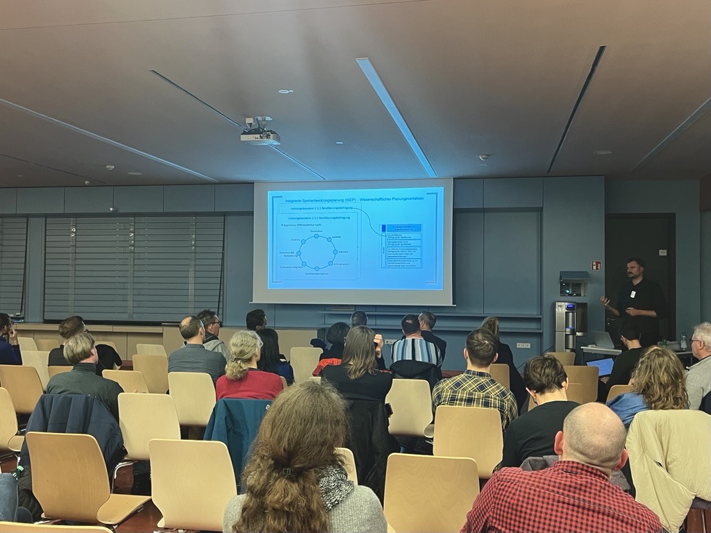 Leinwand mit PowerPoint Präsentation und Publikum