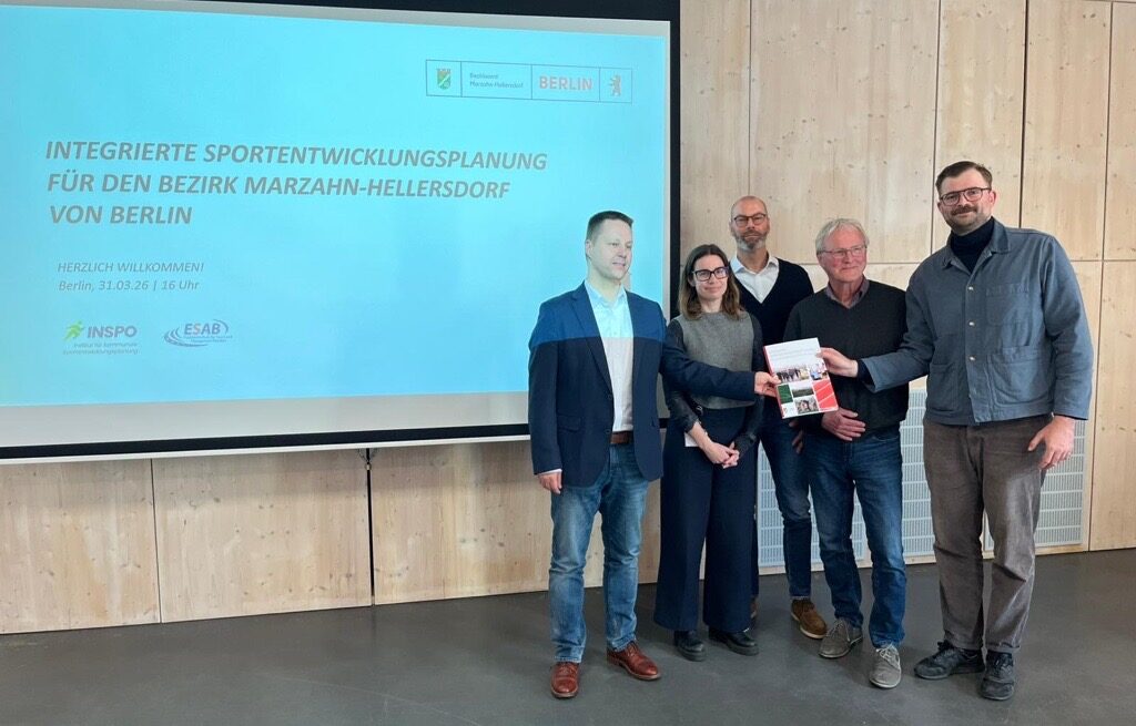 Akteure mit Studie in der Hand vor Präsentationstafel