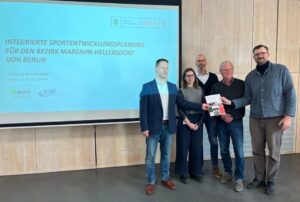 Akteure mit Studie in der Hand vor Präsentationstafel