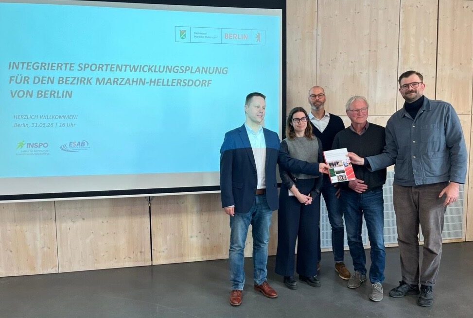 Akteure mit Studie in der Hand vor Präsentationstafel